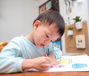 A young boy drawing with crayons