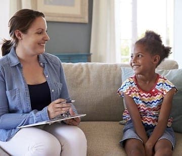 A therapist and a girl talking on a sofa at home