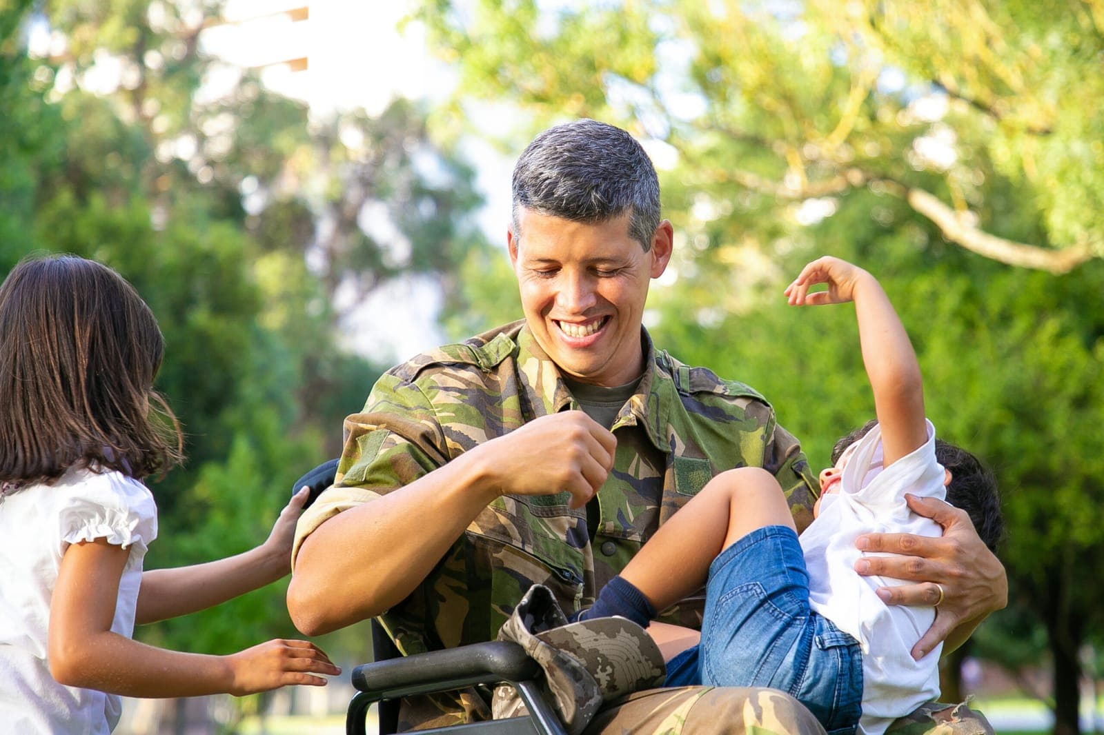 A veteran father in a wheelchair laughing with his two children in a park