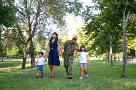 Front view of happy family walking together on meadow in park